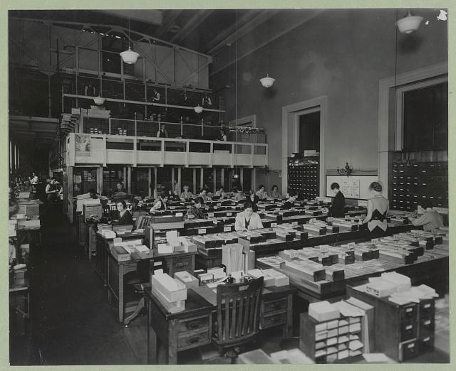 Librarians working with library card catalog drawers in the early twentieth century